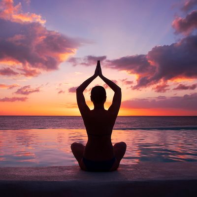 woman-doing-yoga-against-setting-sun